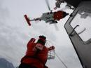 A crew member of US Coast Guard Station Valdez receives a hoist basket from an MH-60 Jayhawk helicopter during rescue hoist training in Port Valdez, Alaska, on September 14. [US Coast Guard photo by Bill Colclough]